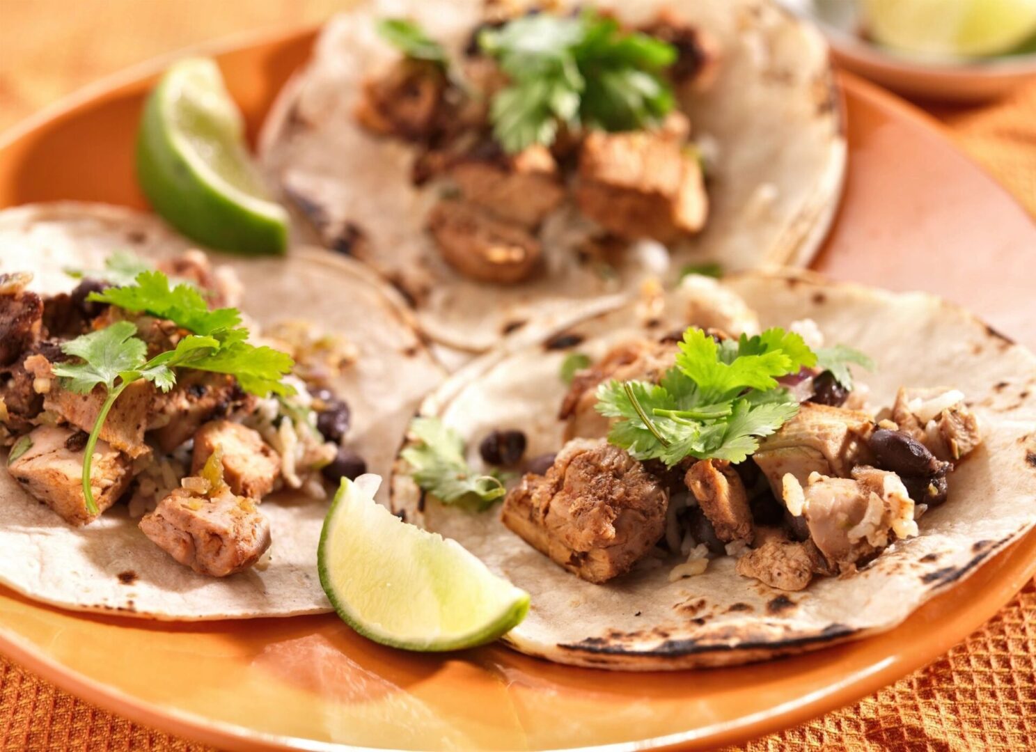 A plate of tacos with lime and cilantro.