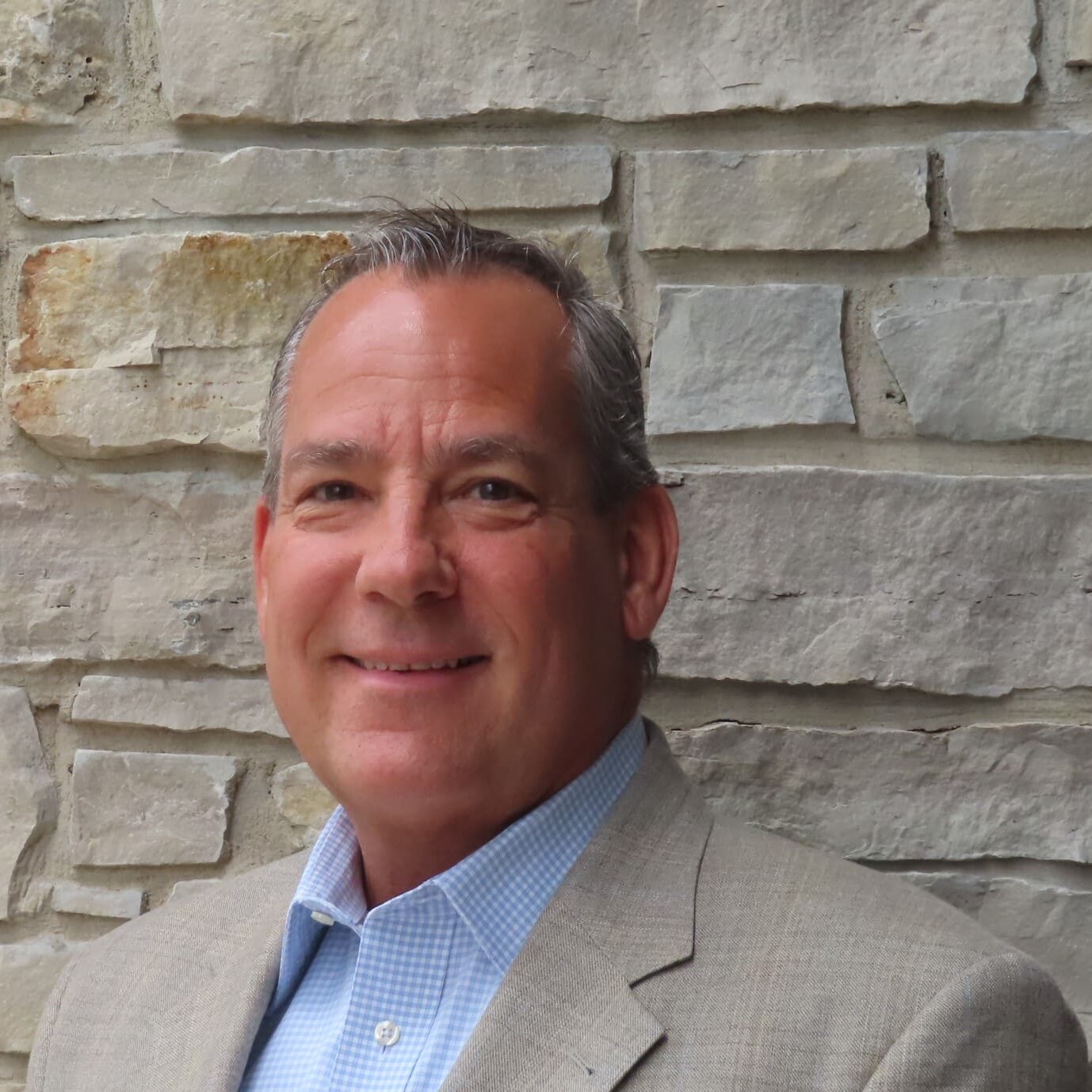 A man in a suit and tie standing next to a brick wall.